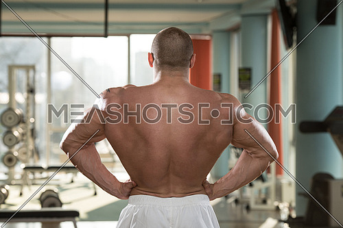Serious Man Standing In The Gym And Flexing Muscles