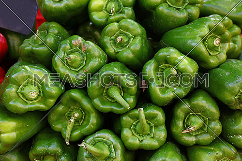 Close up background of fresh green sweet bell peppers on retail display of farmers market, low angle view