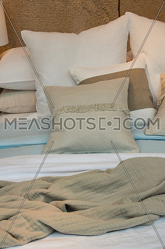 Close up well made bed with pastel color pillows and bedspread, high angle view