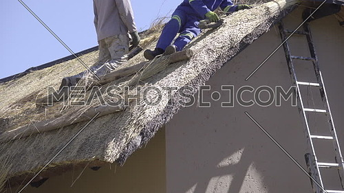 Scene of two African construction workers on roof