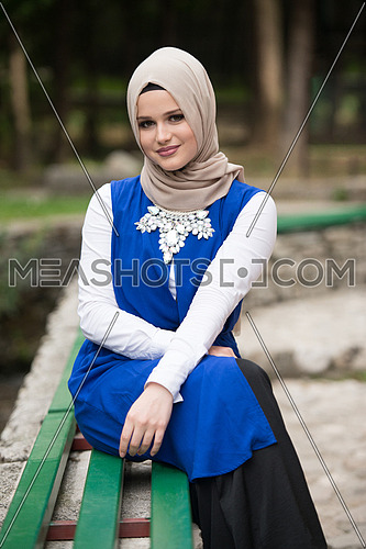Portrait Of Young Muslim Woman Sitting On Bench In Park