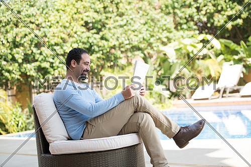 young Middle Eastern man enjoying a coffee in the garden sunny summer morning