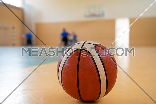 close up photo of a basketball on the court, a sports team of people with disabilities preparing for a game in the background. High quality photo