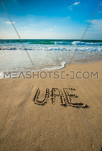 in the picture at the beach  written on the sand UAE