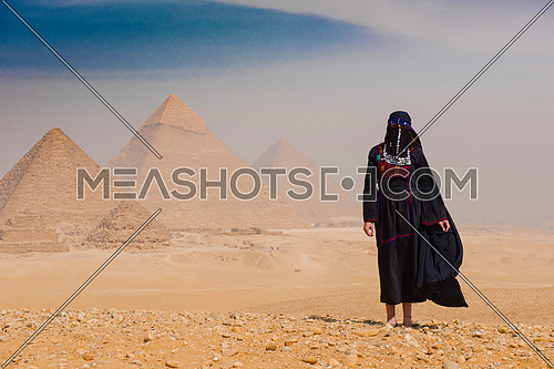famale chello player and woman in traditional egyptian clothes in  ftont of pyramids
