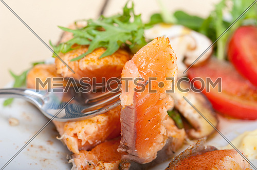 grilled fresh samon filet with vegetables salad tomato arugula mushroomsand paprika on top