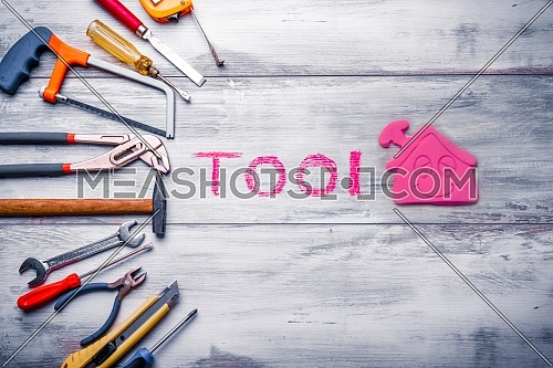 Set of work tool on rustic wooden background with house icon and written 