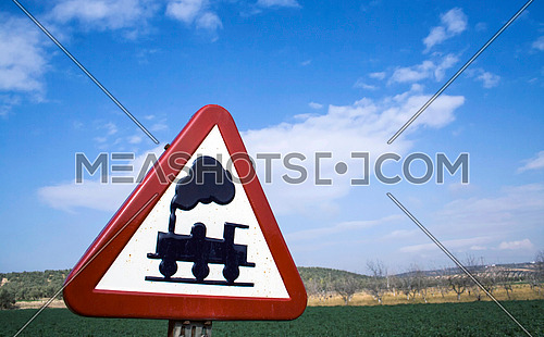 Warning sign worn of level crossing without barriers, blue sky with clouds