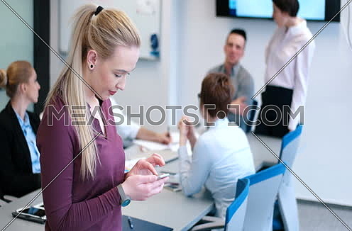Mid-shot for Elegant blond Woman Using Mobile Phone in office interior