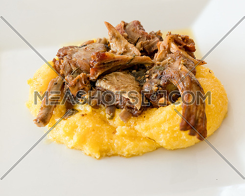 Typical italian food,polenta with Capretto( small goat meat) roasted, close up.