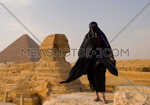 egyptian woman in traditional clothes in front of ancient grea giza pyramids  and sphinx profile
