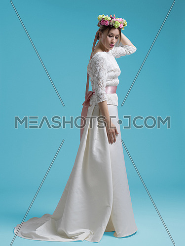 portrait of beautiful young woman as bride in wedding dress isolated on cyan backgrond in studio