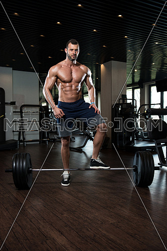 Muscular Man Doing Heavy Weight Exercise For Back With Barbell In Modern Gym