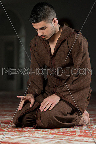Young Muslim Man Making Traditional Prayer To God While Wearing A Traditional Cap Djellaba