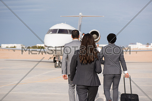 young successful middle eastern business woman walking with their business partners in front of private airplane