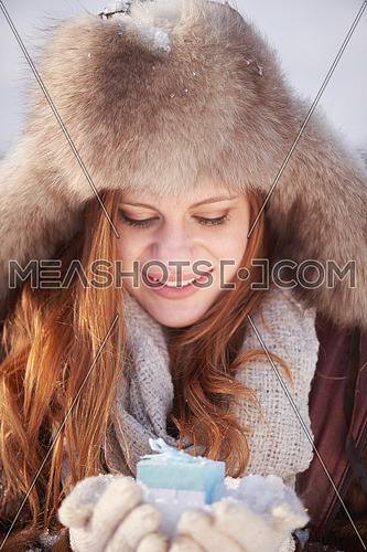 happy young redhair girl  with gift and snow in  hands. Christmas and winter shopping.