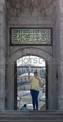 Istanbul, Turkey - April 16 2017: Female tourist taking a selfie photo in front of one of the entrances of the Blue Mosque (Sultan Ahmed Mosque)