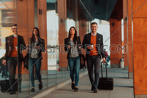 Businessman and businesswoman talking and holding luggage traveling on a business trip, carrying fresh coffee in their hands. Business concept. High-quality photo