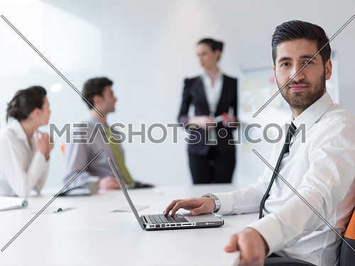 portrait of young modern arab business man with beard at office,   group of  business people  on meeting making presentation  in background