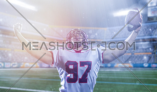 american football player celebrating after scoring a touchdown on big modern stadium field with lights and flares at night