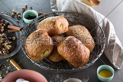 Freshly baked pastry in a metal basket surrounded by nuts and dry food