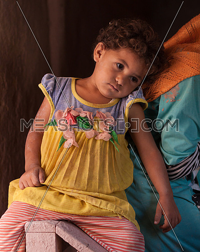 Little girl attached to her elder sister who works at the pottery school in Fayoum, Egypt