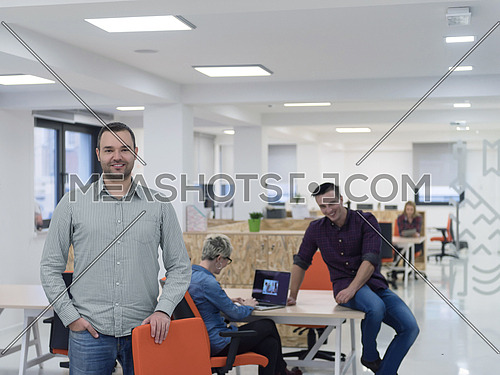 portrait of young businessman in casual clothes at modern  startup business office space,  team of people working together in background
