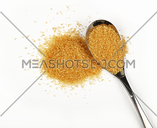 Metal spoon full of brown cane sugar with pinch of sugar spilled around isolated on white background, close up, elevated top view