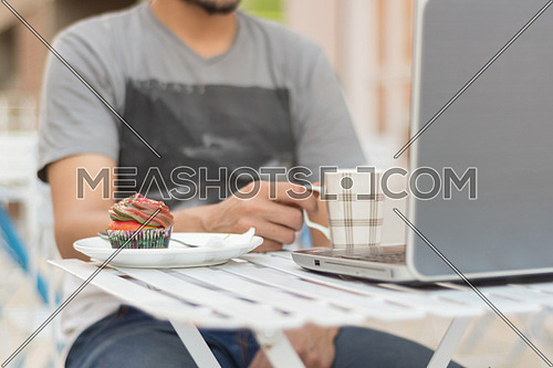 man siting behind a laptop computer holding a mug
