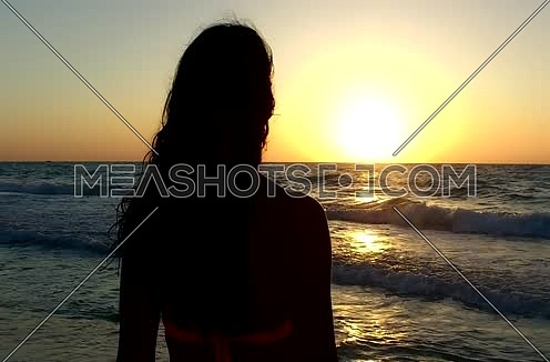 beautiful Woman going into sea during sunset