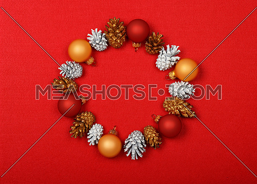 Close up Christmas wrath decoration of white and golden painted cones over red felt background with copy space, table top view, flat lay