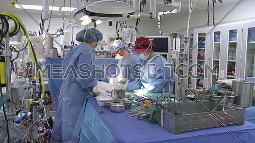 Tilt Down long shot of operating room while medical team performing surgery