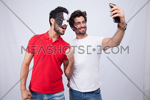 two young men standing on a white background taking a selfie