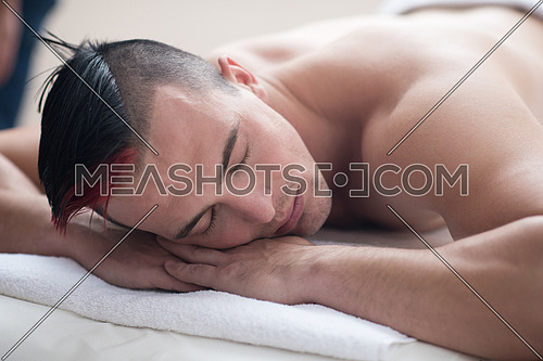 young handsome man have relaxing massage in spa and wellness salon