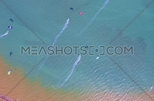 Drone shot flying above the red sea while Kite surfers are surfing  at Day 
