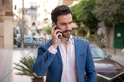 A young man is talking on a mobile phone in the street