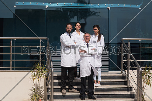 portrait of middle eastern team doctors in front of a large modern hospital