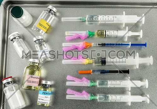 Syringes loaded with medication next to medicine vials prepared in hospital, conceptual image, horizontal composition