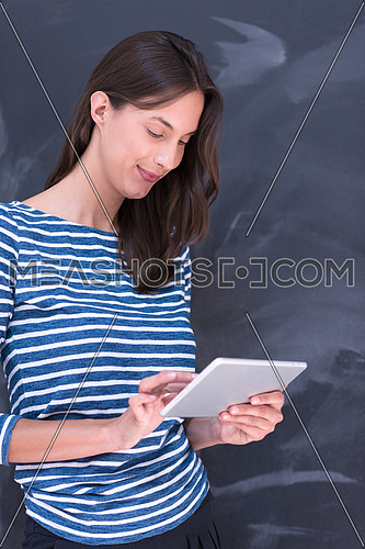 Happy young woman using tablet computer in front of chalk drawing board