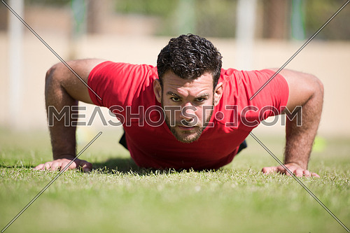 young middle eastern man athlete enjoys doing push-ups outside on a sunny day