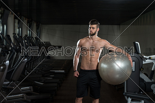 Portrait Of A Young Sporty Man In The Modern Gym With Exercise Ball