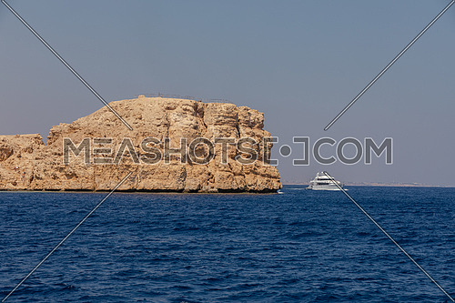 Long shot from Red Sea showing Ras Muhammed Island and a yacht by day