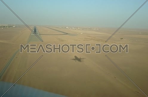 POV shot from plane front showing it's shadow landing at day