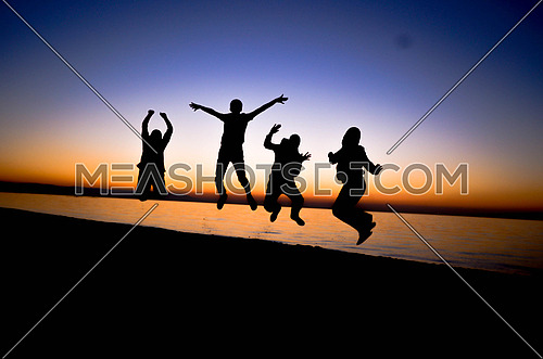four friends jumping at the beach during sunset magic hour