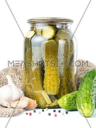 Pickled cucumbers isolated. Pickles in glass jar with garlic and peppercorn isolated on white background. Salted cucumber in jar isolated