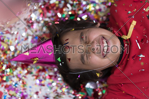 Happy kid celebrating party with blowing confetti while lying on the floor