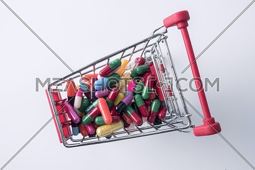Shopping cart with capsules isolated on white background, composition horizontal
