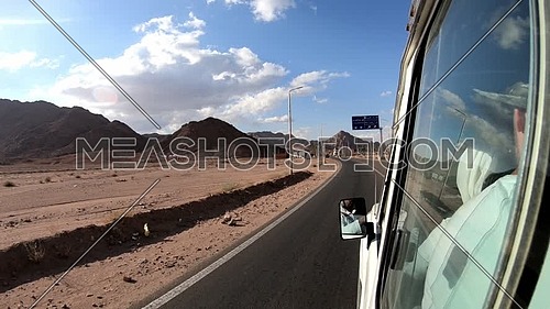 Follow shot for Sinai Mountain from a car driving showing route sign a at day.