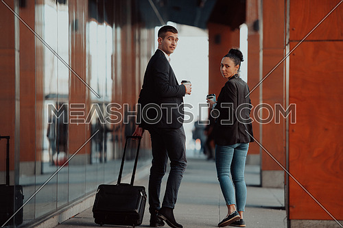businessman with a suitcase walks around town drinking coffee with his colleague
