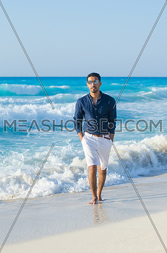 handsome man wearing a short and shirt by the sea